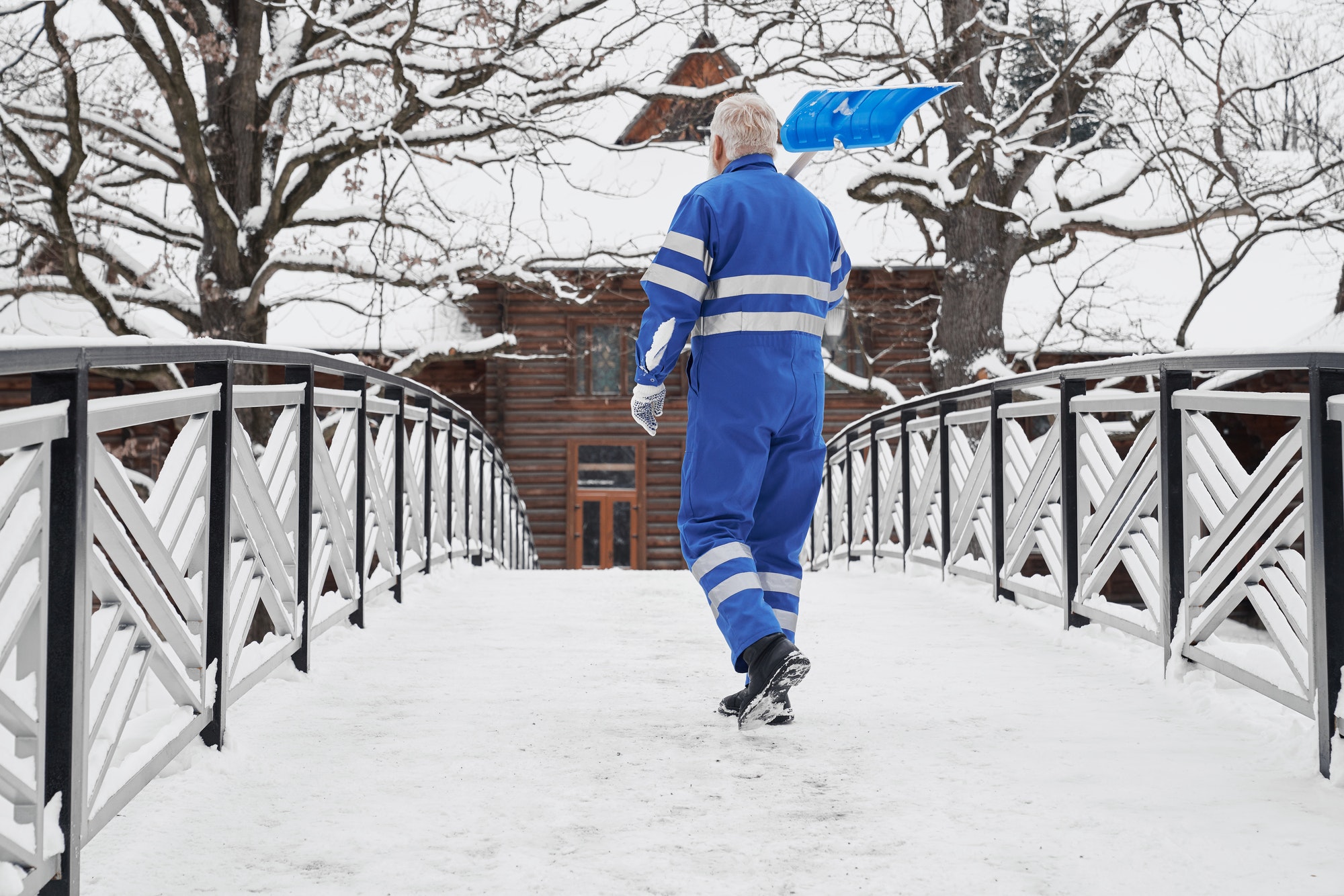 Man with snow shovel on shoulder back view